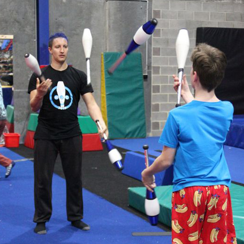 Two young men passing juggling clubs